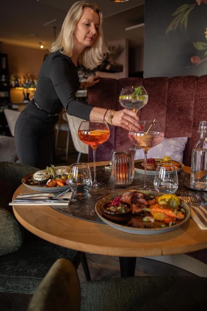 Bediening serveert cocktails aan tafel